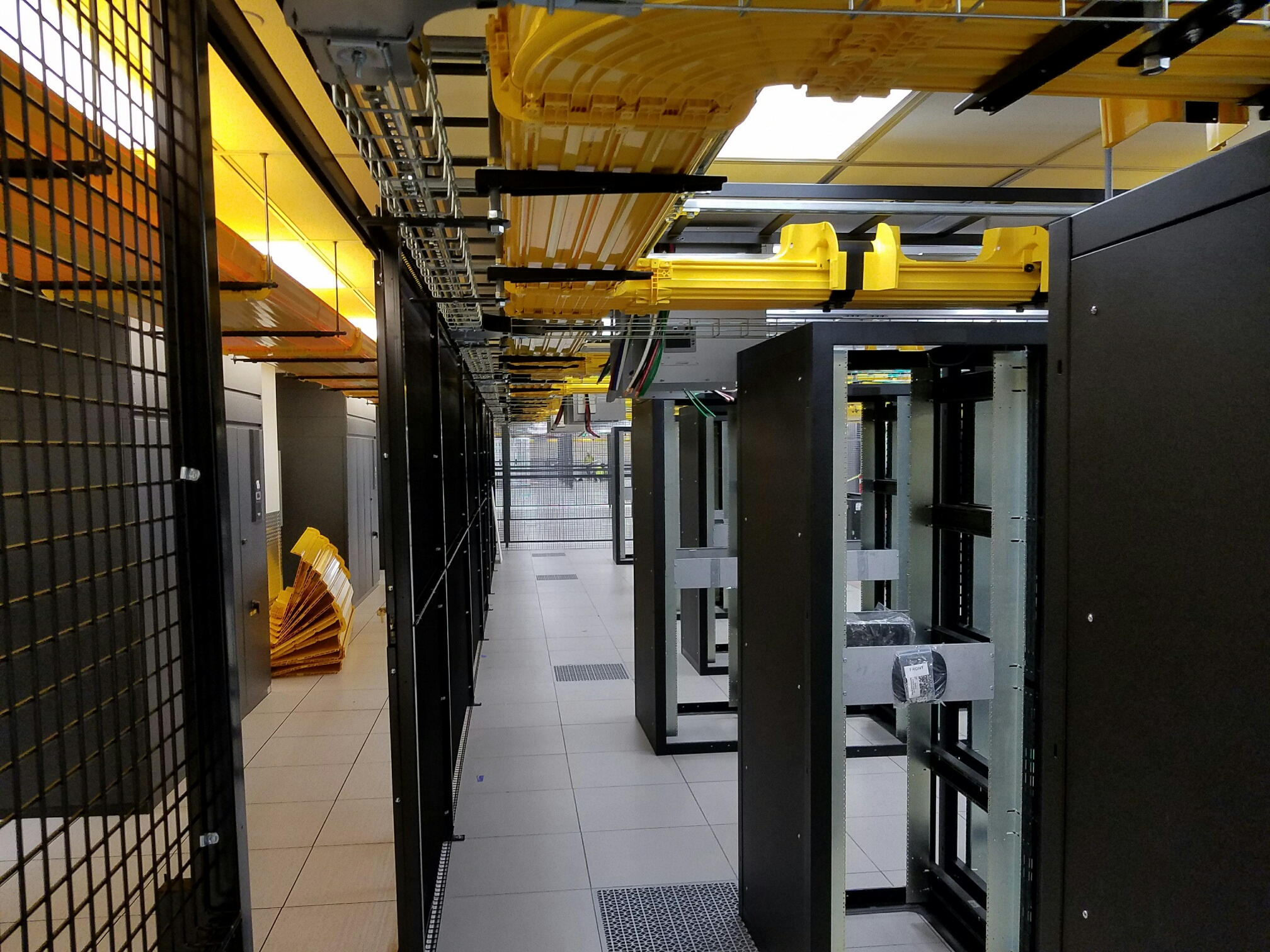 Data center fit out showing racks, overhead conveyance, cable tray and other components.
