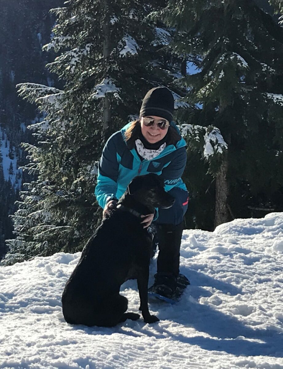 Becky Todd with her Black lab on snowy mountain